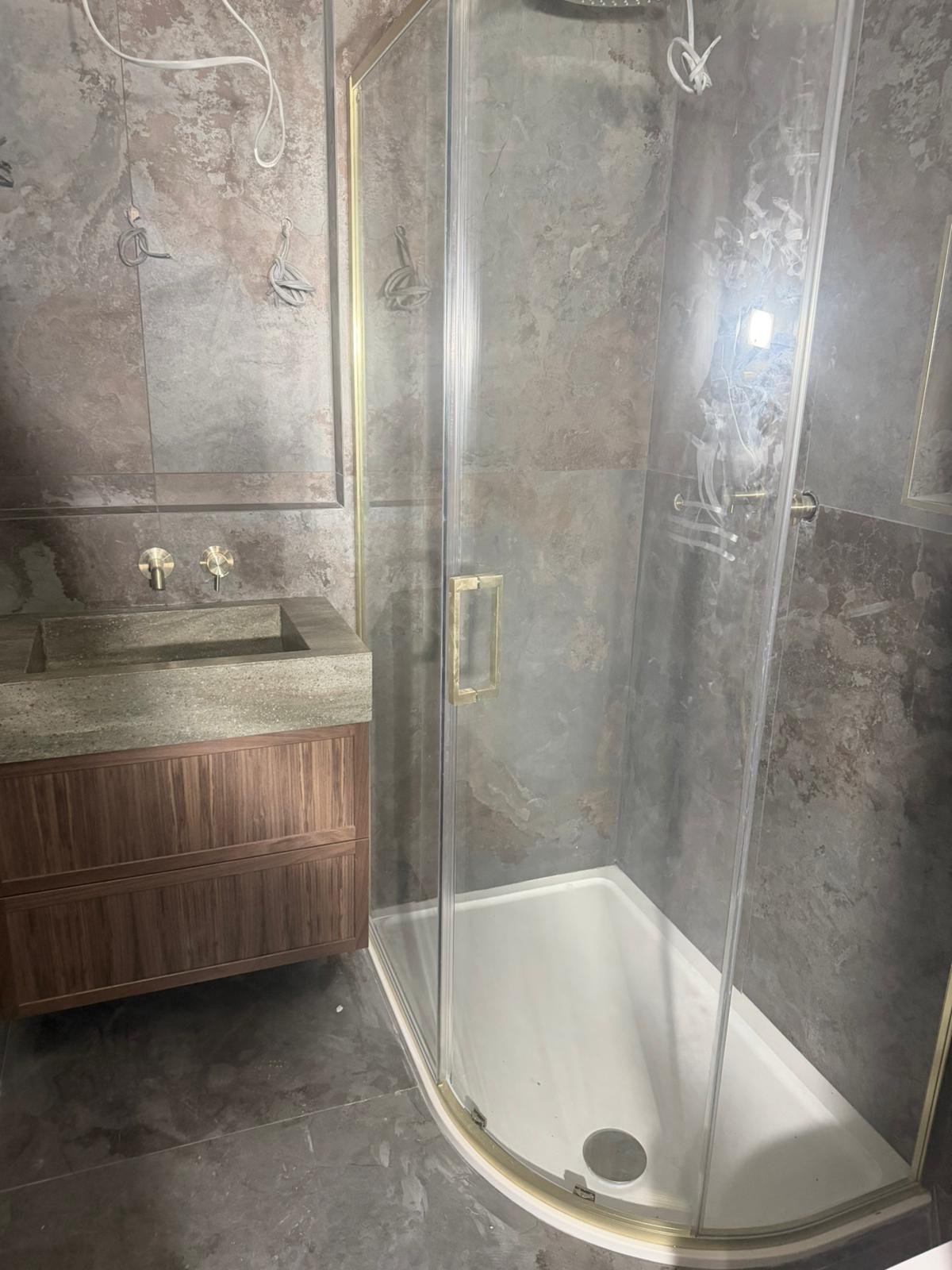 Shower enclosure with walnut vanity and stone sink