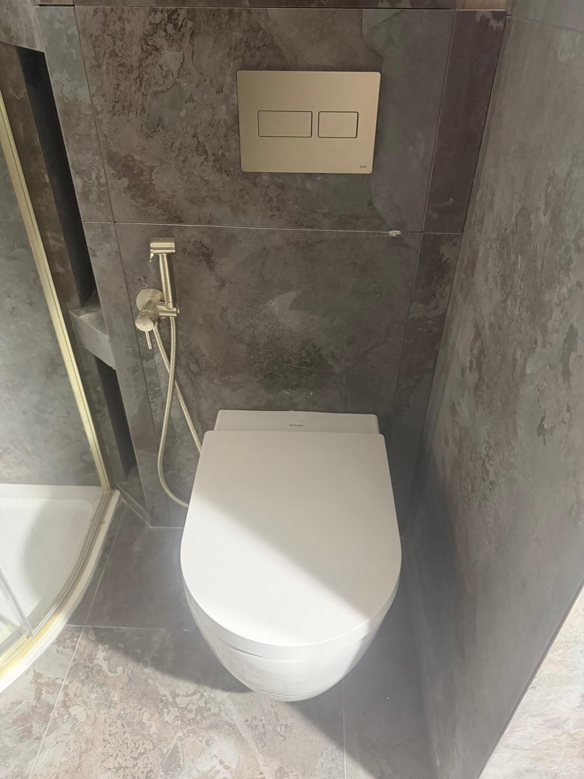 Wall-hung toilet and bidet sprayer with dark marble tiling