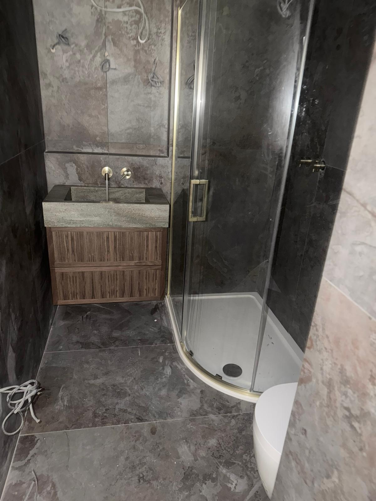 Wide bathroom view with shower and walnut vanity unit