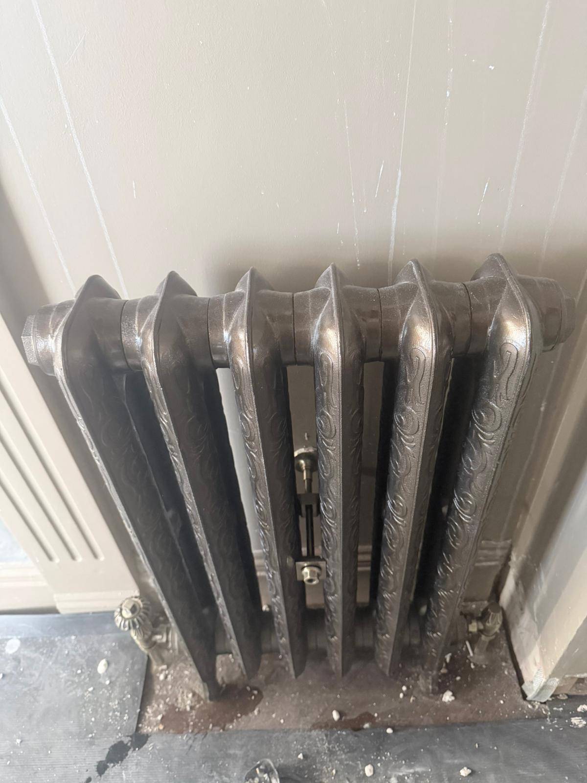 Ornate cast iron radiator close-up with brushed nickel valve