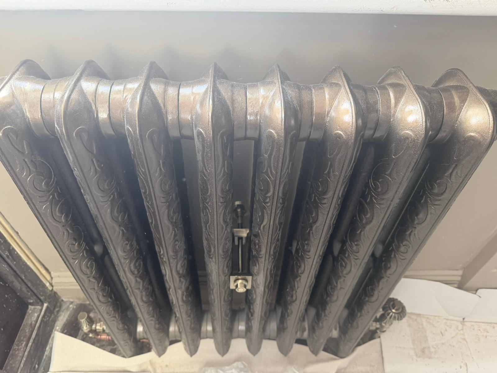 Close-up of ornate cast iron radiator fins and valve